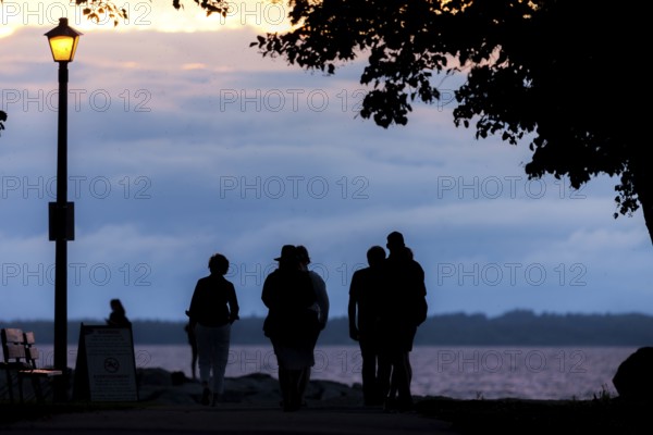 People walking along a tree-lined path at dusk under a streetlamp in Ottawa, Ontario, Canada, North America