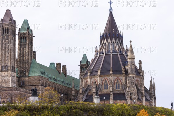 The Canadian Parliament Buildings with Gothic architecture, featuring towers and a prominent spire under a cloudy sky in Ottawa, Ontario, Canada, North America