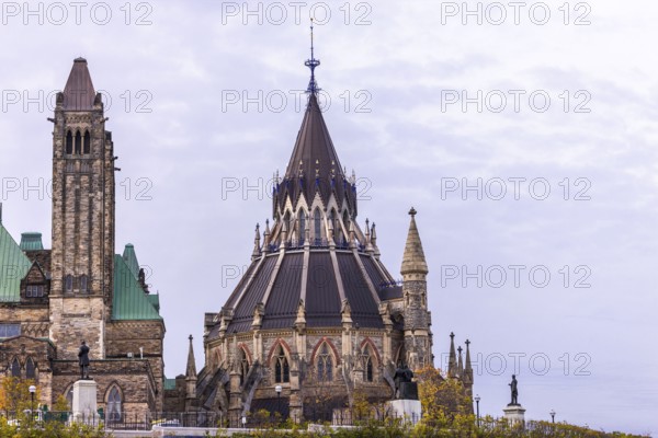 The Canadian Parliament Buildings with an ornate spire and towers against a cloudy sky, showcasing Gothic architectural style in Ottawa, Ontario, Canada, North America