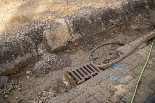 Borken, NRW, Germany, Trench excavation showing earth, mud, gravel, a storm drain, and pipes during roadwork