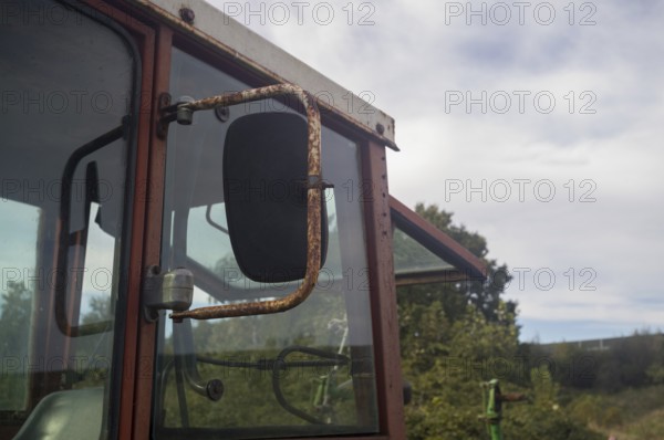 Borken, NRW, Germany, Rusty cabin and side mirror of an old agricultural tractor showing rural decay