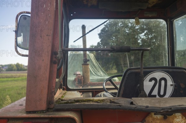 Borken, NRW, Germany, View from inside an old rusty tractor cab looking out at a green farm field