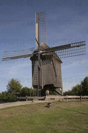 Borken, NRW, Germany, Historic wooden windmill featuring large sails, standing in a green field under a clear blue sky