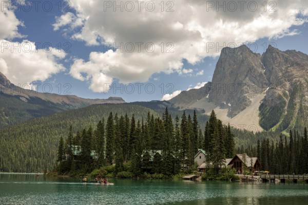 Peaceful Emerald Lake with cabins of Emerald Lake Lodge and forested Canadian Rocky Mountains under a cloud-dotted sky inside Yoho National Park, British Columbia, Canada, North America
