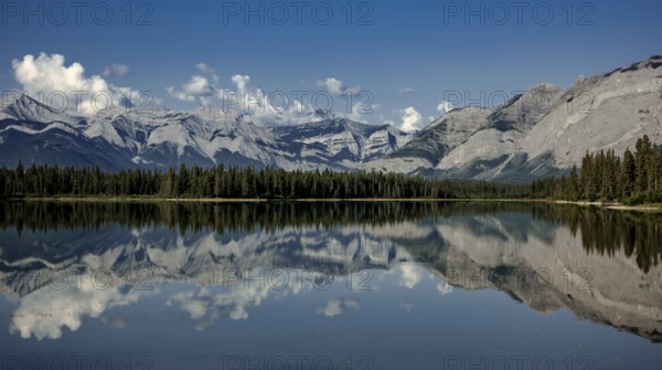 Majestic mountains of the Canadian Rocky Mountains and forest reflected in calm lake under a clear blue sky near Canmore, Alberta, Canada, North America
