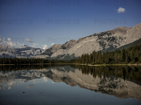 Scenic view of mountains of the Canadian Rocky Mountains mirrored in a still lake on a clear day near Canmore, Alberta, Canada, North America
