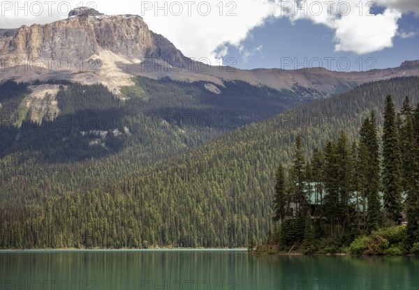 Forested Emerald Lake with the Canadian Rocky Mountains beneath a blue sky and scattered clouds inside Yoho National Park, British Columbia, Canada, North America