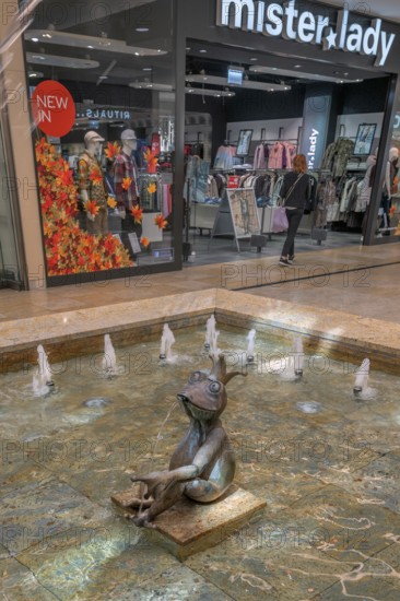 Fashion shop and fountain with frog king and coins in Forum Allgäu, Kempten, Allgäu, Swabia, Germany