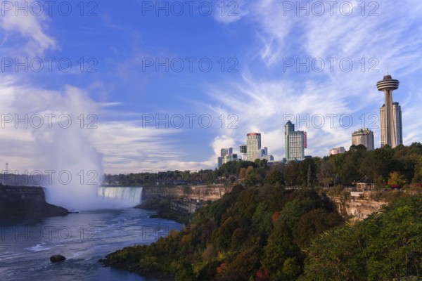 Skyline with prominent tower and the Horseshoe Falls under a bright blue sky in Niagara Falls, Ontario, Canada, North America