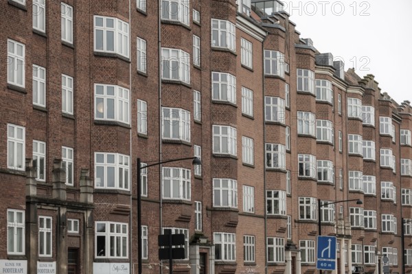 Tall red brick buildings with numerous windows form a continuous urban facade in Aarhus, Denmark, Northern Europe