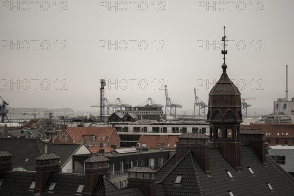 View of a cityscape with rooftops and cranes in the distance under an overcast sky in Aarhus, Denmark, Northern Europe