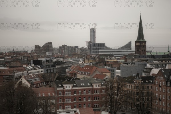 Urban skyline with historic and modern buildings under a gray sky, featuring several towers in Aarhus, Denmark, Northern Europe