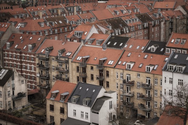 View of a residential area with red-tiled rooftops and brick buildings under a cloudy sky in Aarhus, Denmark, Northern Europe