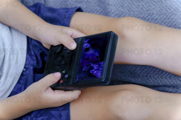 Young child holding and playing a handheld video game console