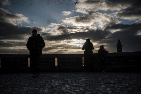 Silhouetted figures at sunset with dramatic clouds and a distant tower in Helsingborg, Sweden, Scandinavia, Northern Europe
