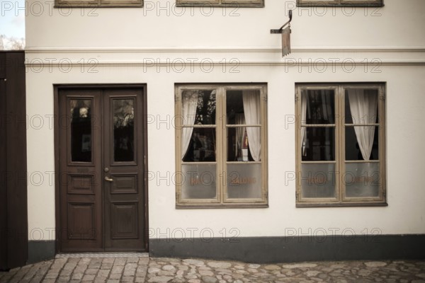 A vintage building facade with wooden doors and windows, featuring cobblestone pavement in Helsingborg, Sweden, Scandinavia, Northern Europe