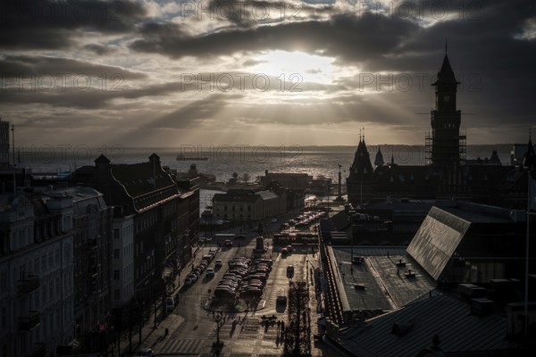 A cityscape at sunset with silhouettes of buildings and clouds overhead and looking out to the Oresund Strait, between Sweden and Denmark, as seen from Helsingborg, Sweden, Scandinavia, Northern Europe