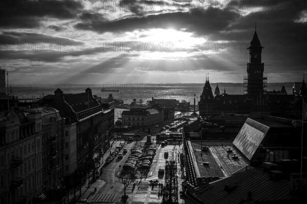 Black and white cityscape with dramatic clouds and sunlight over a harbor and buildings and looking out to the Oresund Strait, between Sweden and Denmark, as seen from Helsingborg, Sweden, Scandinavia, Northern Europe