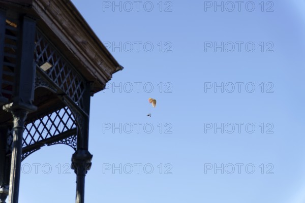 Paramotorist flying with a powered parachute against a bright clear blue sky, next to an old gazebo in ronda, malaga, spain