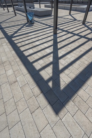 Concrete pavement, blue rubbish bin, long shadows at the state vocational school, Kempten, Allgäu, Swabia, Germany