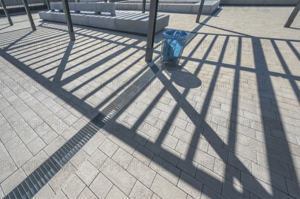Concrete pavement, blue rubbish bin, long shadows at the state vocational school, Kempten, Allgäu, Swabia, Germany