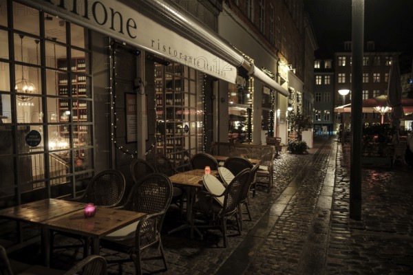 Romantic restaurant exterior at night, featuring tables and candles on a cobblestone street in Copenhagen, Denmark