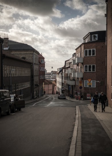 Steep street flanked by residential buildings under a dramatic cloudy sky in Helsingborg, Sweden, Scandinavia