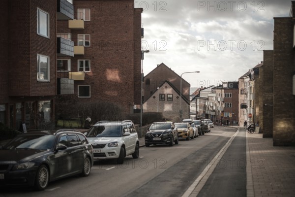 Quiet residential street with parked cars and brick buildings under clouds in Helsingborg, Sweden, Scandinavia