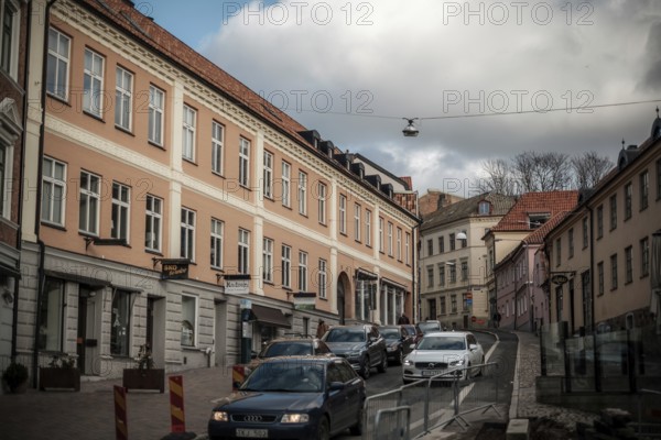 City street with parked cars and pastel-colored buildings under a cloudy sky in Helsingborg, Sweden, Scandinavia