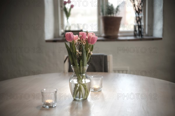 Close-up of a vase filled with tulips on a wooden table, with soft candle lights in Helsingborg, Sweden, Scandinavia