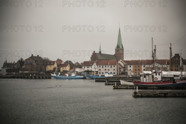 A harbor with docked boats and a church in the background on a cloudy day in Helsingor, Denmark, Northern Europe