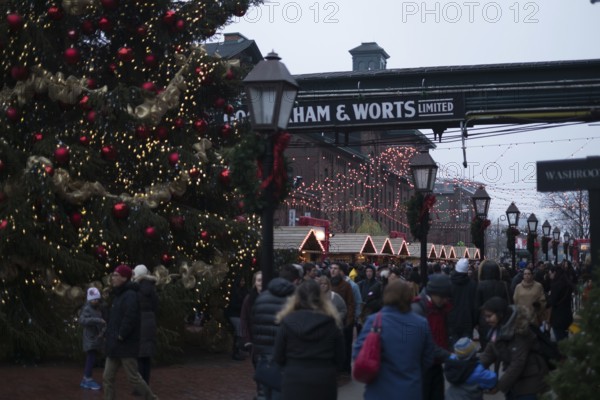 A bustling outdoor Christmas market at the Gooderham and Worts Distillery District, with festive lights and decorations in Toronto, Ontario, Canada, North America