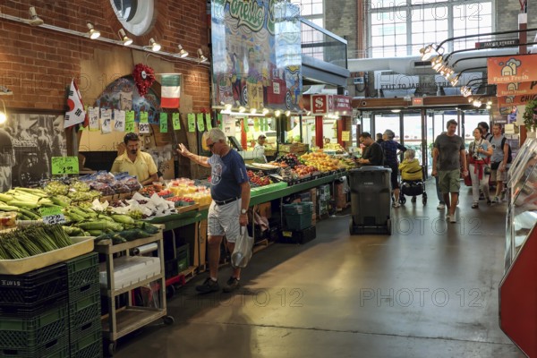 Indoor St. Lawrence Market scene with people browsing stalls filled with colorful produce in Toronto, Ontario, Canada, North America