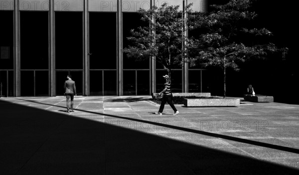 People walking in a modern urban environment with a balance of light and shadow, creating a dynamic city scene in Toronto, Ontario, Canada, North America