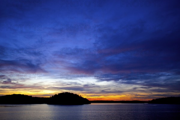 A vivid sunset over a lake, displaying a colorful horizon at twilight in Muskoka, Ontario, Canada, North America