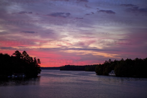 A peaceful sunset paints the sky in vibrant colors over a calm lake in Muskoka, Ontario, Canada, North America