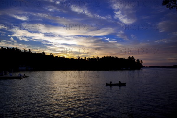 Silhouettes of two canoes on a lake at sunset, creating a peaceful landscape in Muskoka, Ontario, Canada, North America