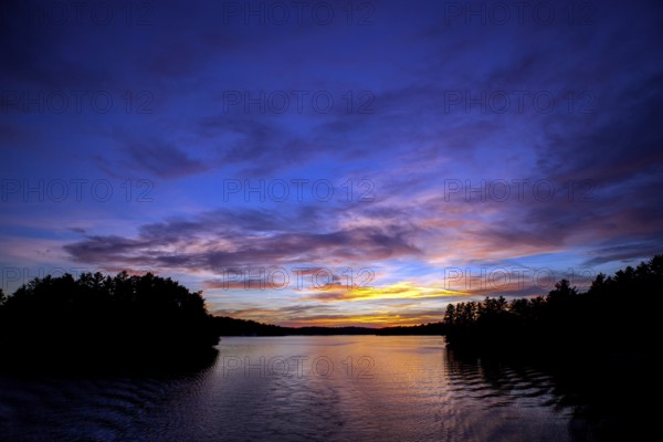 Serene lake at sunset with colorful sky reflections creating a peaceful landscape in Muskoka, Ontario, Canada, North America