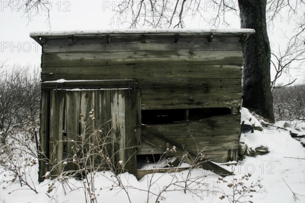 Weathered wooden cabin sits idle in a snowy landscape, conveying abandonment in London, Ontario, Canada, North America