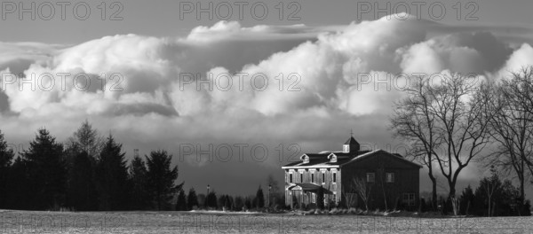 Monochrome image featuring a house against a backdrop of billowing clouds, evoking a serene winter scene in St. Thomas, Ontario, Canada, North America