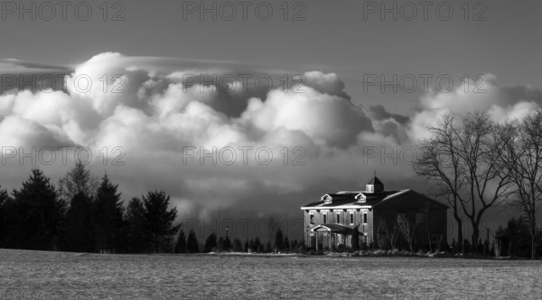 Black and white image of a house with dramatic clouds in the background, creating a moody winter atmosphere in St. Thomas, Ontario, Canada, North America
