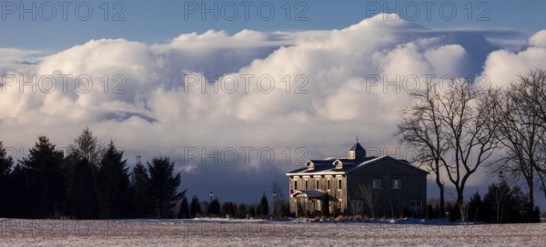 Color image of a house with large clouds in the background, set in a tranquil winter landscape in St. Thomas, Ontario, Canada, North America