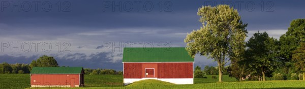 A red barn with green roof sits under a dramatic sky in St. Thomas, Ontario, Canada, North America