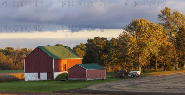 Red barn and trees glow in the golden sunset light in St. Thomas, Ontario, Canada, North America