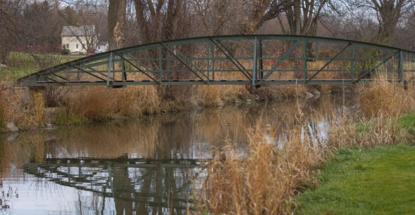 Rustic bridge over a creek with reflections, surrounded by autumn trees and grass, creating a peaceful scene in St. Marys, Ontario, Canada, North America