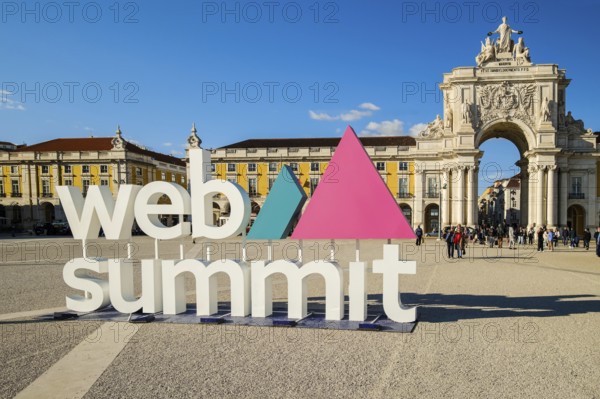 Nov 13, 2024 - Lisbon, Portugal: Web Summit sign displayed at Commerce square on sunny day under clear blue sky, people walking around. Major annual technology conference, internet technology, emerging technology, marketing, AI solution