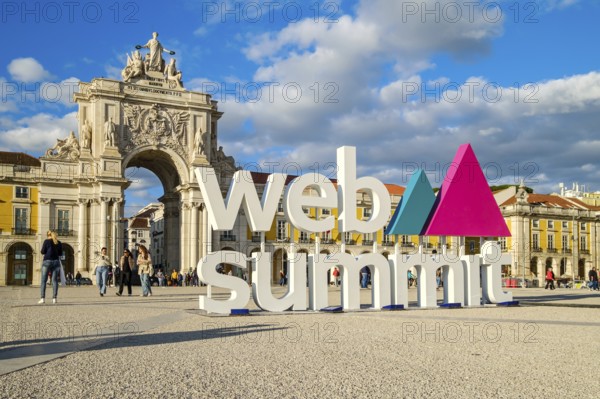 Nov 13, 2024 - Lisbon, Portugal: Big sign Web Summit near iconic Arco da Rua Augusta, beautiful blue sky with some clouds. People walking and taking photos, event, technology, innovation, interaction, exploration, international conference, networking