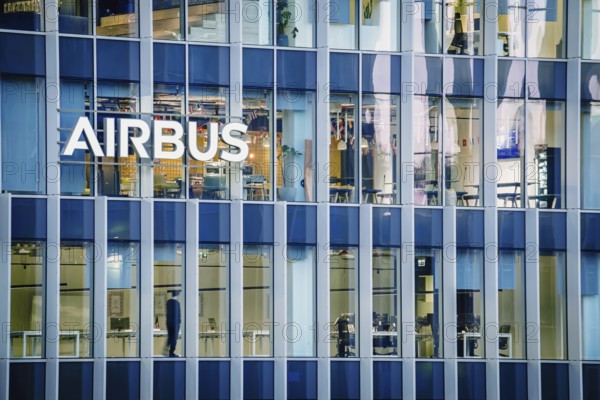 Jan 16, 2025 - Lisbon, Portugal: Day view of the Airbus office building or headquaters with bright illuminated logo and modern glass facade. Interior of workspace with people at desks, leading aerospace company, modern architecture, daily corporate