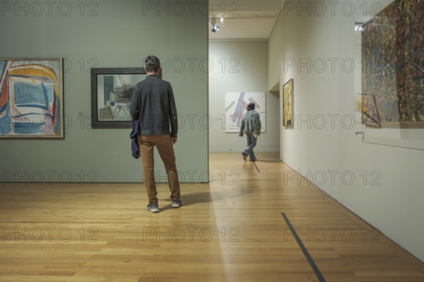 Jan 13, 2024 - Lisbon, Portugal: two visitors explore abstract artworks displayed on walls of Centro Cultural de Belem known as Berardo Museum, Lisbon, Portugal. One person contemplating contemporary artwork, other walking further into gallery