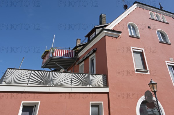 Blue sky, red façade with dormers, chimneys and balcony in Kisslegg, Allgäu, Baden-Württemberg, Germany